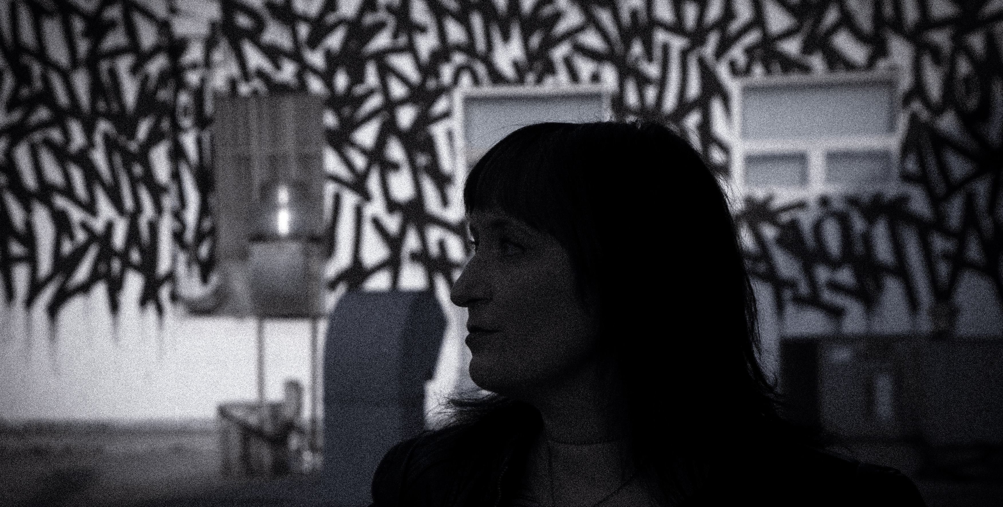 black and white silhouette of author in from of high contrast graffitied warehouse